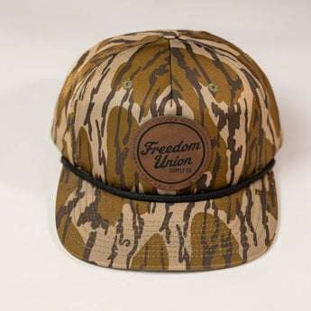 Camouflage-patterned cap with a brown leather patch on a white background