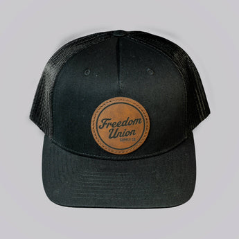 Black cap with a leather patch featuring 'Freedom Union' on a light gray background