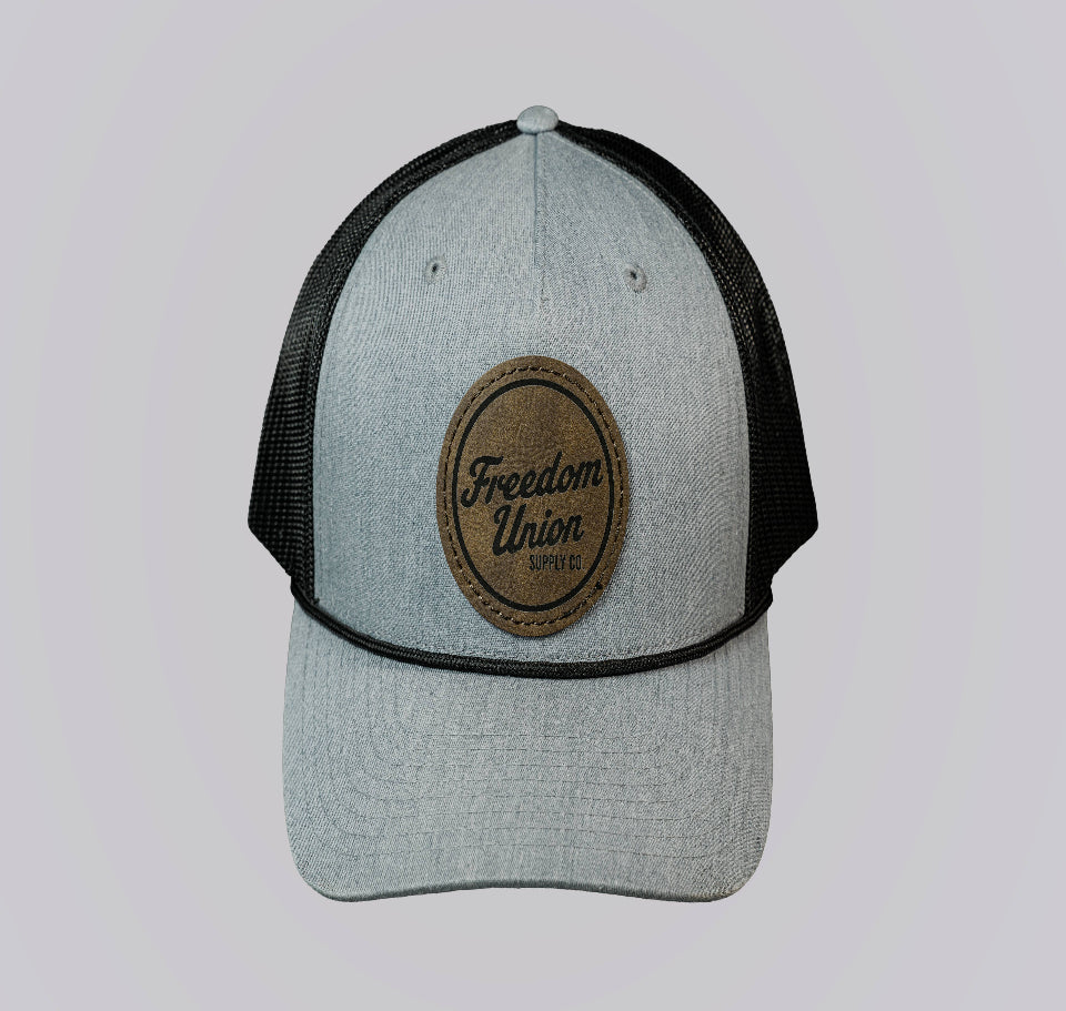 Gray and black cap with a brown leather patch on a light gray background
