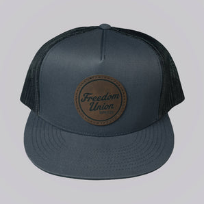 Gray cap with a brown leather patch on a light gray background