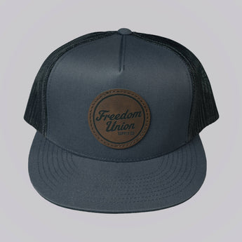 Gray cap with a brown leather patch on a light gray background