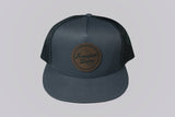 Gray cap with a brown leather patch on a light gray background