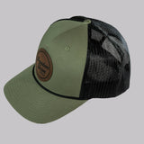 Green and black trucker cap with leather patch on a gray background