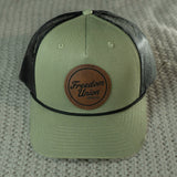 Green cap with brown leather patch on a textured surface