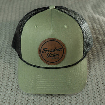 Green cap with brown leather patch on a textured surface