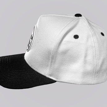 White cap with black brim on a gray background
