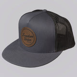Gray trucker cap with a brown leather patch on a light gray background