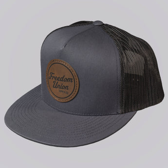 Gray trucker cap with a brown leather patch on a light gray background