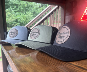 Gray black and olive Freedom Union trucker hats with leather patch logo