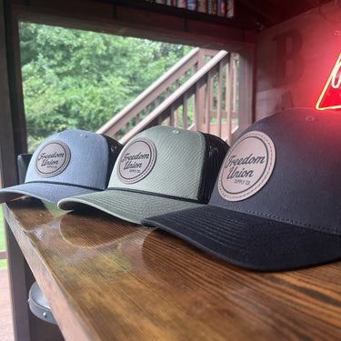 Gray black and olive Freedom Union trucker hats with leather patch logo