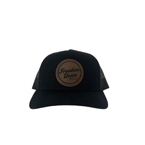 Black suede snapback hat with brown circular Freedom Union logo patch