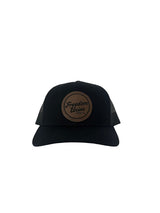 Black suede snapback hat with brown circular Freedom Union logo patch